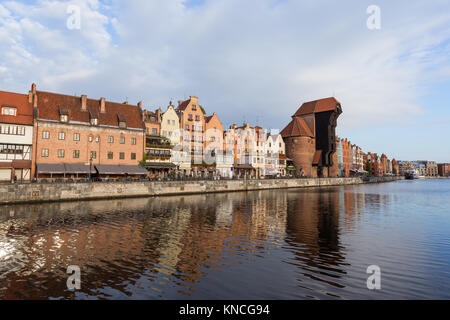 Blick auf den Kran und andere alte Gebäude entlang der Langen Brücke Waterfront und ihre Reflexionen über die Mottlau in der Innenstadt von Danzig. Stockfoto