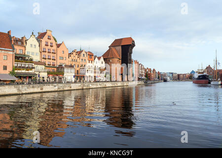 Blick auf den Kran und andere alte Gebäude entlang der Langen Brücke Waterfront und ihre Reflexionen über die Mottlau in der Innenstadt von Danzig. Stockfoto