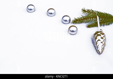 Weihnachten Hintergrund weiß und silber mit Kugeln, ein Kiefer Zweig und ein Silver Pine Cone Anhänger im Schnee liegend Stockfoto
