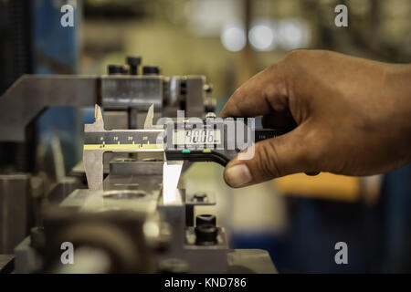 Factory mann Arbeitnehmer messen Stahl Detail mit Digitaler Messschieber in Werkstatt Stockfoto