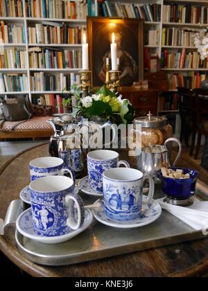 In der Nähe von Kaffee oder Tee mit feinem Porzellan Tassen und Untertassen in der gemütlichen Bibliothek mit Bücherregalen im Hintergrund Stockfoto