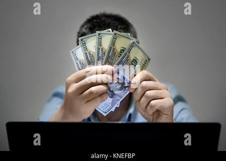 Nahaufnahmen der Hände shopping online mit Laptop halten US-Dollar. Das Ergebnis. Freelancer glaubt, dass sein Gehalt. Einfach Geld. Arbeit im Internet Stockfoto