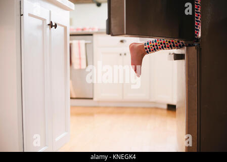 Junge Mädchen klettern in einen Kühlschrank Stockfoto
