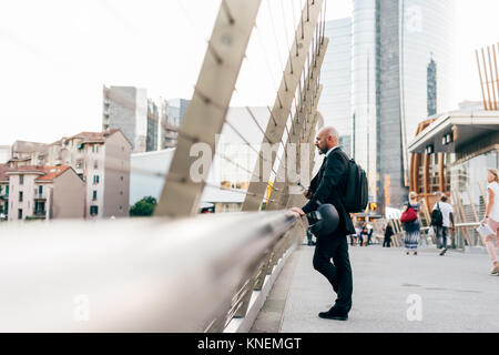 Reifen Geschäftsmann auf der Brücke, an Aussicht suchen, Holding smartphone Stockfoto