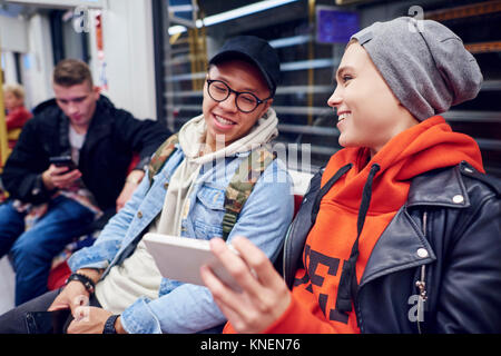Junge Paare, die noch in der U-Bahn Station am Smartphone suchen Stockfoto