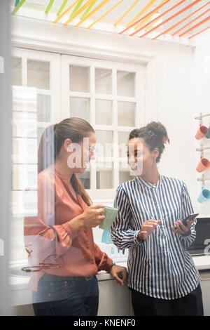 Zwei Geschäftsfrauen lacht während einer Kaffeepause im Büro Küche Stockfoto