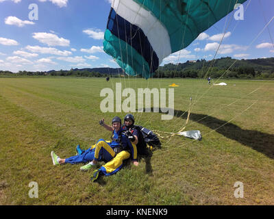 Portrait von Tandem skydivers Daumen hoch geben nach der Landung Stockfoto