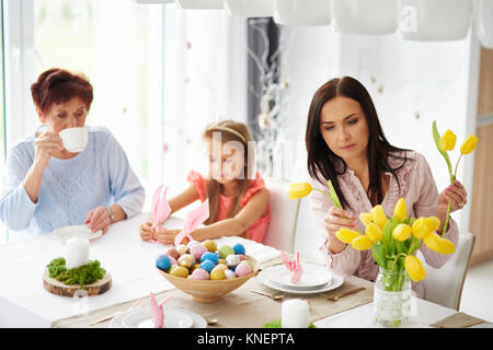 Frau mit Tochter und Mutter, die die gelbe Tulpen an Ostern Esstisch Stockfoto