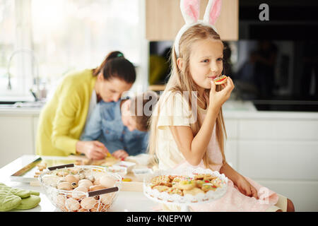 Mädchen essen Ostern Kekse auf den Küchentisch Stockfoto