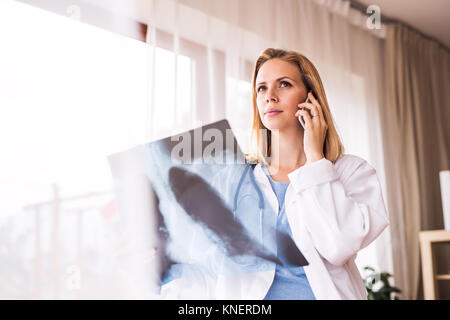 Ärztin mit Smartphone und x-ray. Stockfoto