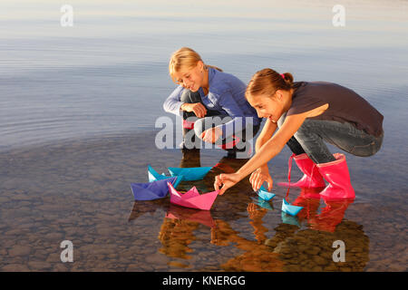 Zwei junge Mädchen floating Papier Boote auf dem Wasser Stockfoto