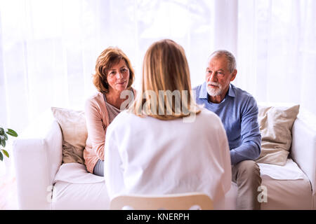 Ärztin im Gespräch mit einem älteren Ehepaar. Stockfoto