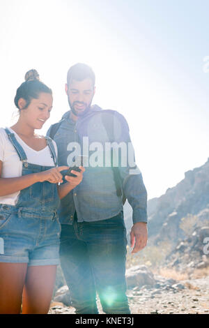 Die jungen wandern Paar an Smartphone in sonnendurchfluteten Tal suchen, Las Palmas, Kanarische Inseln, Spanien Stockfoto
