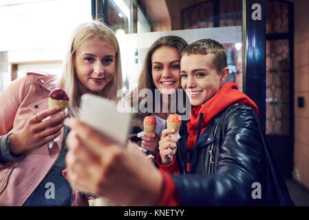 Drei junge Frauen mit Eistüten, Smartphone selfie auf Stadt. Stockfoto