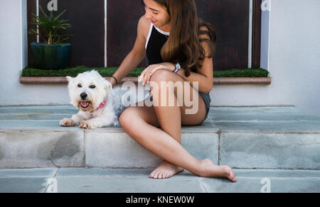 Junges Mädchen sitzen auf der Terrasse Treppe Streichelzoo Hund Stockfoto
