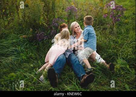 Eltern und Kinder im hohen Gras liegend zusammen Stockfoto