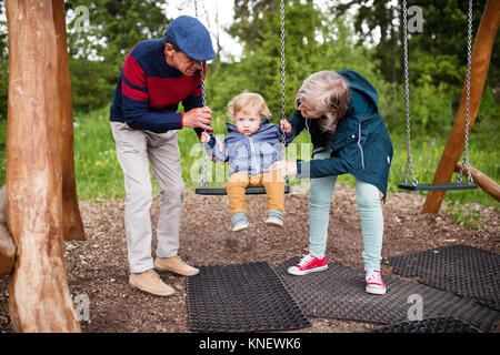 Senior Paar mit kleinen Jungen auf dem Spielplatz. Stockfoto