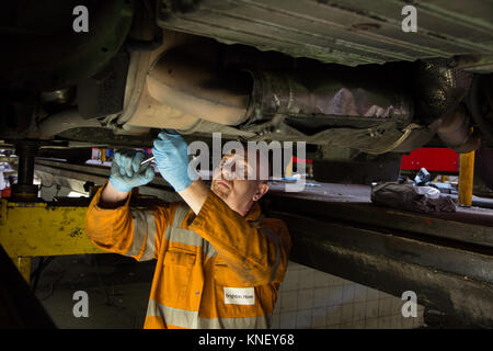 Ein Mechaniker Arbeiten am Motor mit einem Bus von unten an der Brighton und Hove Bus Depot Stockfoto