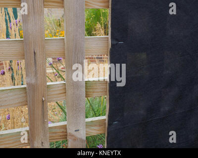 Offener Garten GITTER MIT SCHWARZEM STOFF GEHEFTET INNERHALB SO ABSCHIRMUNG DER ÖLTANK im hinteren Garten- HAUS Stockfoto