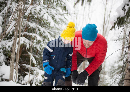 Mann und Sohn nach unten im Schnee bedeckt Wald Stockfoto