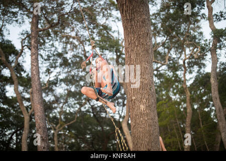 Junge Schwingen am Seil im Baum Stockfoto