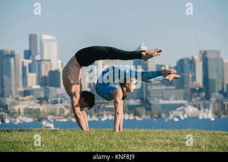 Junges Mädchen und jungen Mann, Draußen, Balancieren auf Händen in Yoga Position Stockfoto