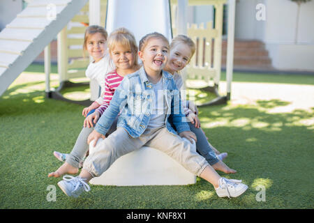 Mädchen und Jungen in der Vorschule, Porträt sitzen auf dem Spielplatz im Garten Stockfoto