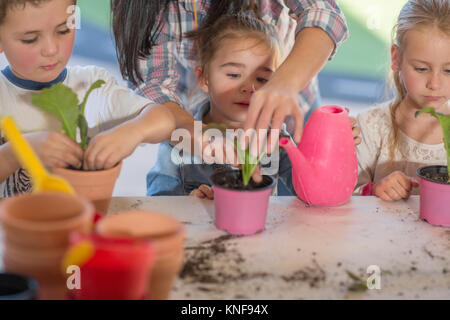 Mitte der erwachsenen Frau Hilfe für junge Kinder mit Gartenarbeit Aktivität Stockfoto