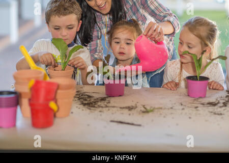 Mitte der erwachsenen Frau Hilfe für junge Kinder mit Gartenarbeit Aktivität Stockfoto