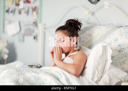 Mädchen im Bett blasen Nase auf Taschentuch Stockfoto