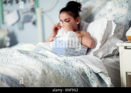 Mädchen im Bett blasen Nase auf Taschentuch Stockfoto