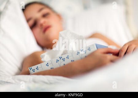 Mädchen im Bett Holding Box von Geweben Stockfoto