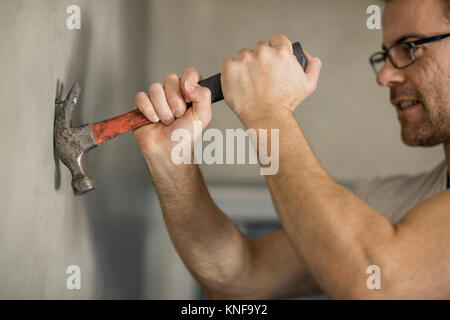 Mann Nagel aus der Wand, mit dem Hammer Stockfoto