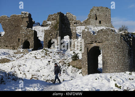 Ein Wanderer besucht die schneebedeckten Dunamase Ruinen der Burg auf dem Felsen von Dunamase in Aghnahily, Co Laois. Stockfoto