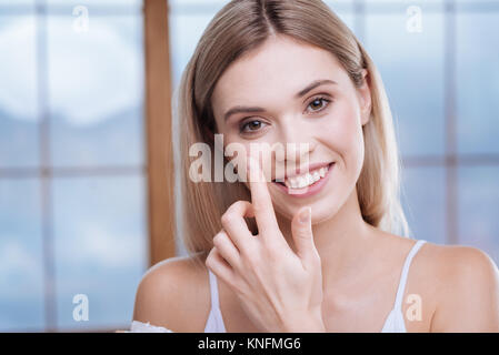 Adorable Frau Anwendung Creme in ihre Wangen Stockfoto
