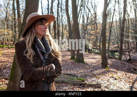 Frau gekleidet in Outdoor Kleidung an Bäumen in Broxbourne Woods, Hertfordshire suchen Stockfoto