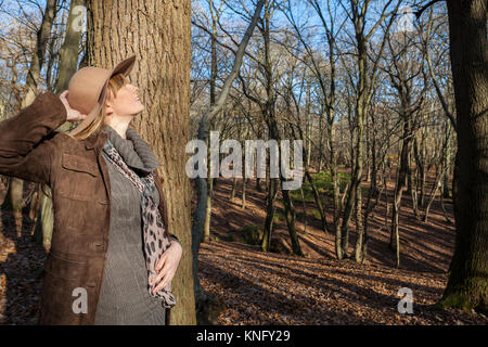 Frau gekleidet in Outdoor Kleidung an Bäumen in Broxbourne Woods, Hertfordshire suchen Stockfoto