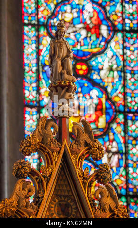 BUNTGLASFENSTER DER ELY CATHEDRAL IM HINTERGRUND MIT GESCHNITZTER FIGUR IM VORDERGRUND, ELY, CAMBRIDGESHIRE Stockfoto