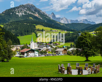 Ein Kreis von Stühlen aus Holz kennzeichnet eine der Powerspots in Filzmoos. Filzmoos Dorf mit dem Rotelstein und der Dachstein im Hintergrund. Österreich, Stockfoto