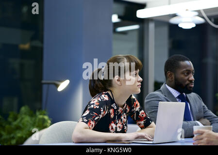 Kaukasische Geschäftsfrau mit einem Laptop und schwarze männliche Kollegen in einem Team Meeting in einem modernen Büro Stockfoto