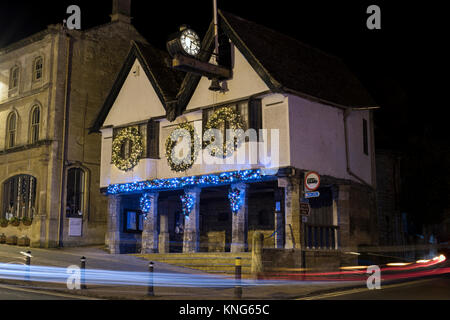 Weihnachten Kranz Dekorationen und Lichter auf dem Tolsey Museum bei Nacht. Burford, Cotswolds, Oxfordshire, England Stockfoto