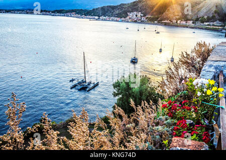 Boote segeln bei Sonnenuntergang entlang der Klippen Küste in der Nähe der Stadt von Taormina Sizilien Italien Stockfoto