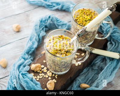 Chia gerollt oat Pudding über Nacht Porridge mit Quinoa, Banane, Pistazien, Milch. Eine Tasse gesundes Frühstück Stockfoto