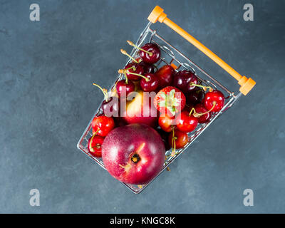 Frische rote Früchte und Beeren, Kirschen, Pfirsiche und Erdbeeren - im Supermarkt Warenkorb Fach auf schwarzem Hintergrund. Platz kopieren Stockfoto