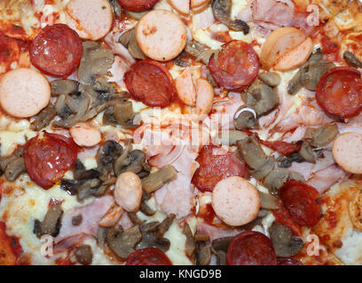 Leckere Pizza zum Mitnehmen mit würzigen Salami Würstel Champignons und Schinken Stockfoto