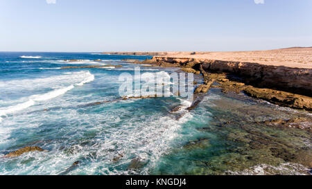 Luftaufnahme von felsigen Klippen, Riff, Wellen, türkisfarbene Wasser des Atlantik auf Fuerteventura, Kanaren, Spanien. Stockfoto