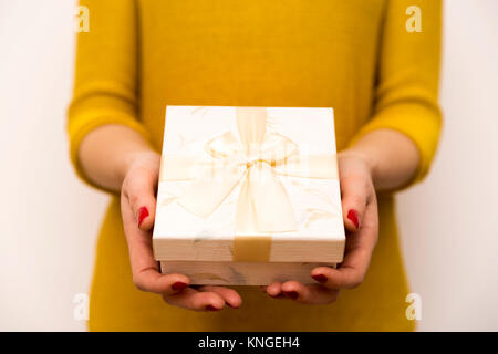 Woman Holding in den Händen weißer Geschenkbox mit goldenen Bogen Stockfoto