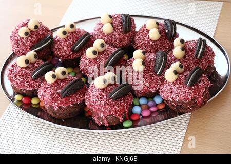 Gruppe von Muffins verkleidet als ein Monster Familie mit großen Augen und großen Lippen auf einem silbernen Tablett präsentiert Stockfoto