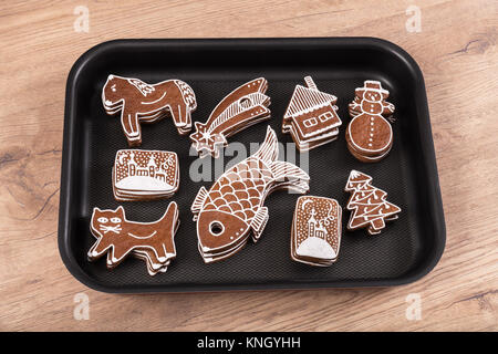 Schönen traditionellen handgemachten Weihnachten Lebkuchen. Ein Backblech mit Stapeln von Hand dekoriert Kekse auf einem Holztisch. Stockfoto