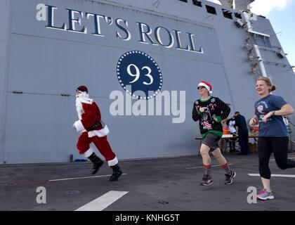 Ein Weihnachtsmann Imitator rennen US-Segler während ein Rentier Laufen am Weihnachtstag an Bord der USN San Antonio-Klasse amphibious Transport dock Schiff USS Somerset am 25. Dezember 2016 in das Arabische Meer. (Foto von MCS 2 Jakob I. Allison über Planetpix) Stockfoto